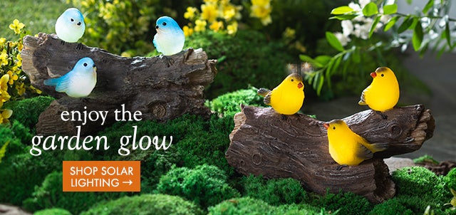 Image of Solar-Lighted Three Bluebirds on a Log Outdoor Sculpture and Solar Lighted Yellow Finches on a Log Garden Sculpture lit up at night. enjoy the garden glow. SHOP SOLAR LIGHTING