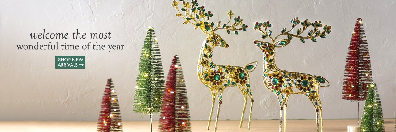 image of beaded gold deer and lighted bottle brush trees on console table. welcome to the most wonderful time of the year.  SHOP NEW ARRIVALS