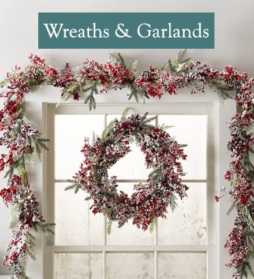 A frosted Edinburg red berry wreath and garland adorn a window in winter