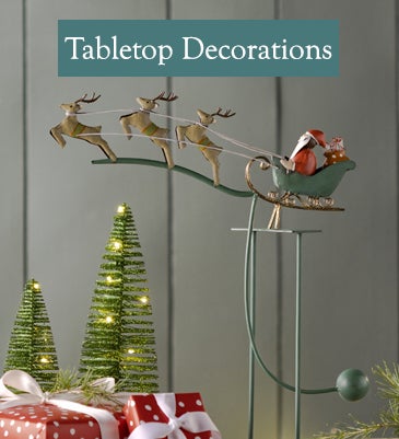 A vintage-style metal santa and reindeer balancing toy rocks on a holiday table