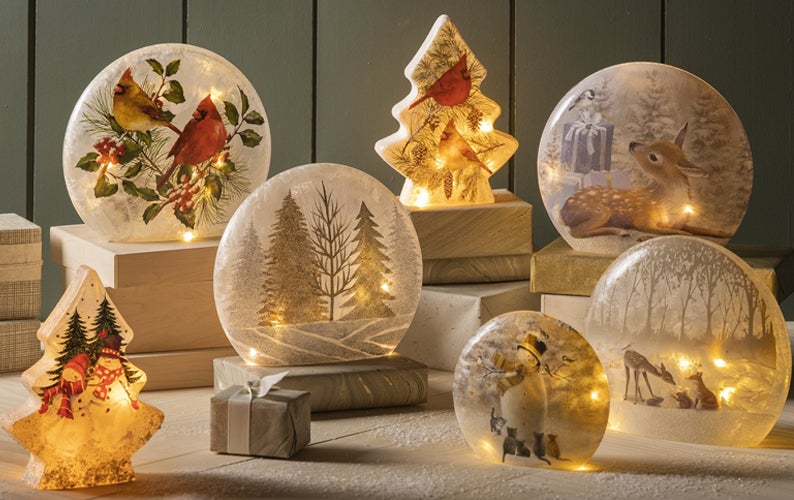 An array of lighted tabletop accents with holiday scenes of deer, snowmen and cardinals